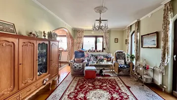 Geräumiges Wohnzimmer mit traditionellen Möbeln, Parkettboden und Stuckelementen an der Decke.