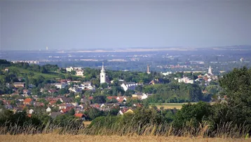 Panoramablick auf eine malerische Stadt mit Kirchtürmen, umgeben von grünen Hügeln und Feldern.