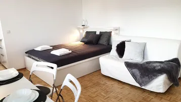 Helles Studio-Apartment mit Schlafbereich, Sofa und Esstisch, ideal für Einzelpersonen oder Paare.