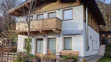 Charmantes Haus im alpinen Stil mit Holzbalkon und kleiner Terrasse im Vorgartenbereich.