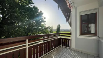 Sonniger Balkon mit weitem Blick über die grüne Landschaft und die umliegende Natur.