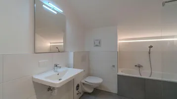 Modernes Badezimmer mit Waschbecken, Toilette, Badewanne und indirekter LED-Beleuchtung.