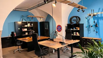 Geräumiges Büro mit gewölbten Decken, blauen Wänden und mehreren modernen Arbeitsplätzen.