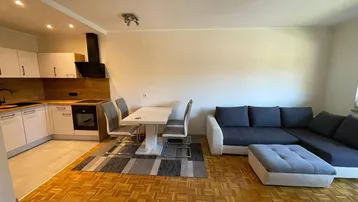 Heller offener Wohn- und Essbereich mit moderner Küche und gemütlichem Sofa.