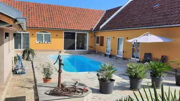 Innenhof mit einem erfrischenden Swimmingpool, umgeben von einer gepflasterten Terrasse und mediterranen Pflanzen.