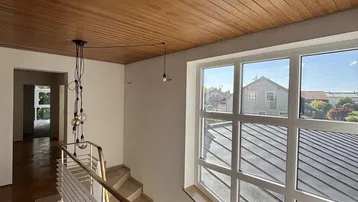 Treppenaufgang mit Holzdecke, modernem Geländer und großen Fenstern mit Fernblick.