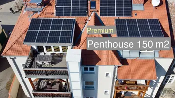 Luftaufnahme eines Gebäudes mit Ziegeldach und installierten Solarpaneelen, das ein Penthouse zeigt.