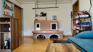 Gemütliches Wohnzimmer mit Holzboden, einem dekorativen Kamin und Regalen für Stauraum.