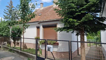 Ansicht des Hauses von der Straße mit einem kleinen Vorgarten und geschlossenen Rollläden.