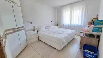 Helles Schlafzimmer mit Doppelbett, weißem Kleiderschrank und hellem Laminatboden.