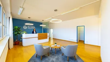 Moderner Empfangsbereich mit Rezeptionstheke, Sitzgelegenheiten und Firmenlogo an der Wand.