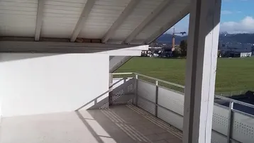 Überdachter Balkon mit Fliesenboden und weitem Blick ins Grüne.