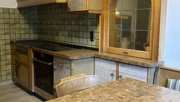 Traditionelle Küche mit Holzarbeitsplatten, integriertem Backofen und rustikalen Schränken.
