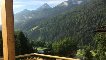 Balkon mit Holzboden und Geländer bietet einen atemberaubenden Blick auf die umliegenden Berge und Wälder.