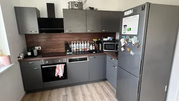 Moderne Küche mit grauen Schränken, Holzarbeitsplatte und integrierten Geräten.