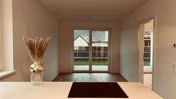 Moderne Küche mit Kochinsel und Blick auf den Garten durch große Terrassentüren.