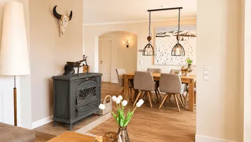 Heller Essbereich mit Holztisch und Kaminofen, offen zum Wohnzimmer.