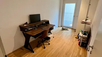 Helles Arbeitszimmer mit Holzboden, modernem Schreibtisch und direktem Zugang zum Balkon.