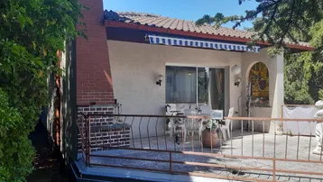 Große Terrasse mit Gartenmöbeln, integriertem Grillbereich und Markise, ideal für Mahlzeiten im Freien.