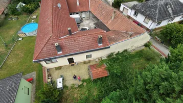 Luftaufnahme eines U-förmigen Anwesens mit Innenhof, Garten und kleinem Pool.