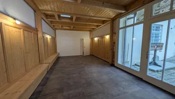 Geräumiger Innenbereich mit Holzbalkendecke, Holztäfelung und großen Fenstern zum Hof.