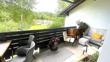 Möblierter Balkon mit Holzzaun und Blick ins Grüne, ideal zum Entspannen im Freien.