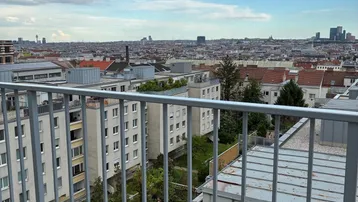 Blick von einem Balkon über die Stadtlandschaft mit zahlreichen Gebäuden und einem weiten Himmel.