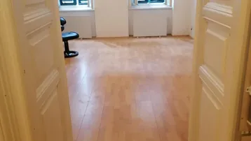 Heller Raum mit Holzboden und zwei Fenstern mit Fensterläden, bereit zur individuellen Gestaltung.