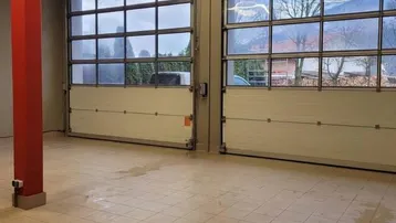 Geräumige Doppelgarage mit Fliesenboden und großen Sektionaltoren mit Fenstern.