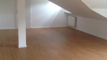 Heller Dachgeschossraum mit Laminatboden, weiß gestrichenen Wänden und schräger Decke.