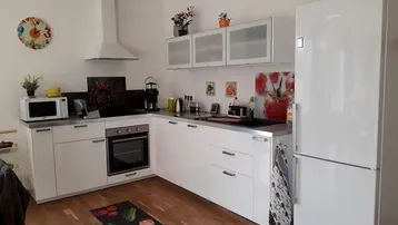 Moderne Einbauküche mit weißen Hochglanzfronten, integrierten Geräten und hellem Holzparkettboden.