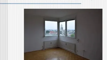Leeres Zimmer mit Eckfenster, das einen Blick auf die Stadt bietet.