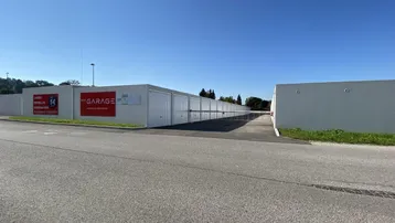 Reihe von weißen Garagenboxen entlang einer Zufahrtsstraße unter blauem Himmel.
