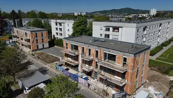 Luftaufnahme von Neubauten in Rohbauweise mit umliegenden Wohngebäuden und grüner Umgebung.