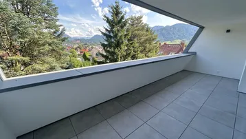 Geräumiger Balkon mit modernen Fliesen und weitem Blick auf die umliegende Landschaft und Berge.