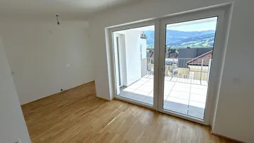 Helles Zimmer mit Parkettboden und Zugang zu einem Balkon mit Bergblick.