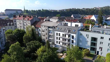 Luftaufnahme einer Wohnsiedlung mit verschiedenen Gebäudetypen und viel Grünfläche in städtischer Umgebung.