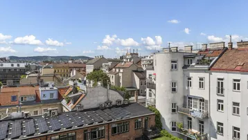 Panoramablick über die Dächer der Stadt mit historischen Gebäuden und modernen Solaranlagen.
