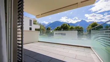 Geräumiger Balkon mit Fliesenboden und beeindruckendem Bergblick unter blauem Himmel.