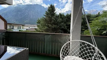 Gemütlicher Balkon mit Hängesessel und Bergblick, ideal zum Entspannen im Freien.