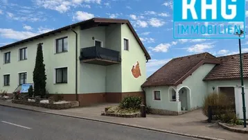 Ansicht des Wohnhauses von der Straße mit Balkon und gepflegtem Vorgarten.