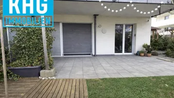 Große gepflasterte Terrasse mit kleinem Rasenbereich und Zugang zum Gebäude.