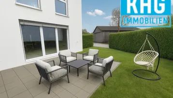 Moderne Terrasse mit Gartenmöbeln und Schaukelstuhl, umgeben von einer grünen Hecke und Rasenfläche.