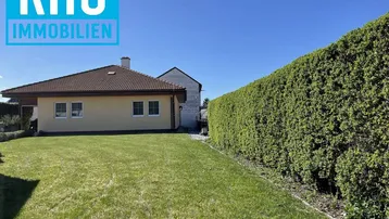 Gepflegter Gartenbereich mit Rasenfläche und einer hohen Hecke, die Privatsphäre bietet.