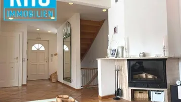 Eingangsbereich mit Kamin und Holztreppe, der zu den oberen Etagen führt.