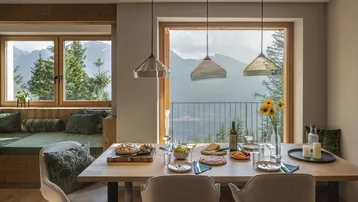 Heller Essbereich mit großem Fenster, Bergblick und gemütlicher Sitzbank.