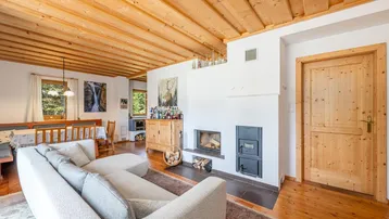 Gemütliches Wohnzimmer im alpinen Stil mit Holzbalkendecke, Kamin und traditionellen Holzmöbeln.