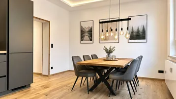 Moderner Essbereich mit Holztisch, bequemen Stühlen und indirekter Deckenbeleuchtung auf Eichenparkett.