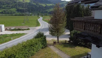 Weitläufiger Blick auf die Landstraße und die umliegende grüne Landschaft mit Bergen.