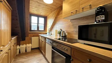 Gemütliche Küche im Dachgeschoss mit Holzverkleidung, Einbaugeräten und Fenster.